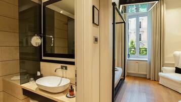 Un baño moderno con un espejo grande, un lavamanos blanco y una cabina de ducha con mampara de vidrio.