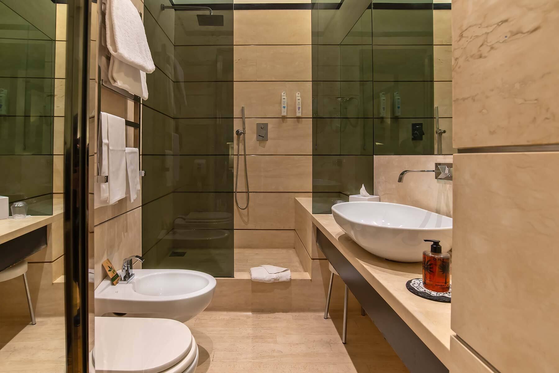 A modern bathroom with two sinks, a glass-enclosed shower, and a toilet.