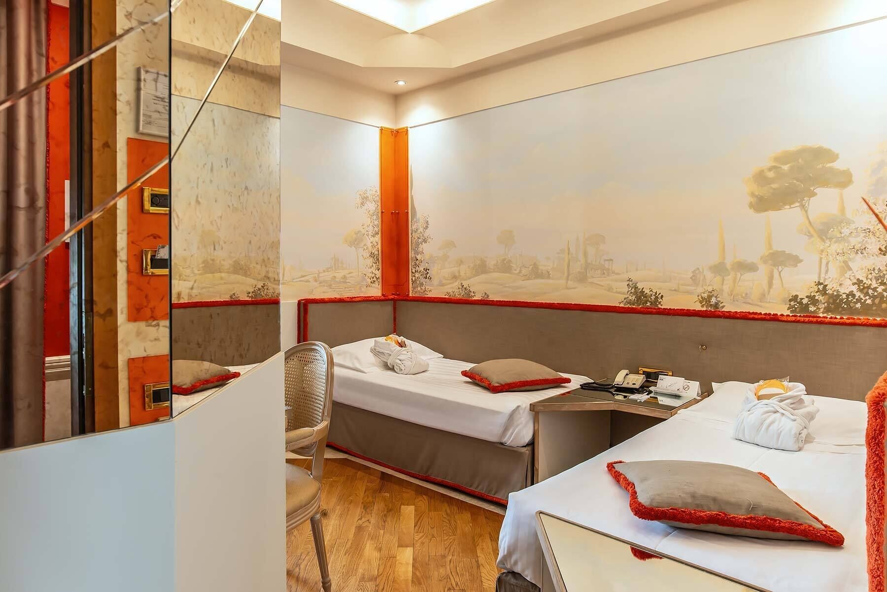 A hotel room with two beds, a small desk, and a chair.