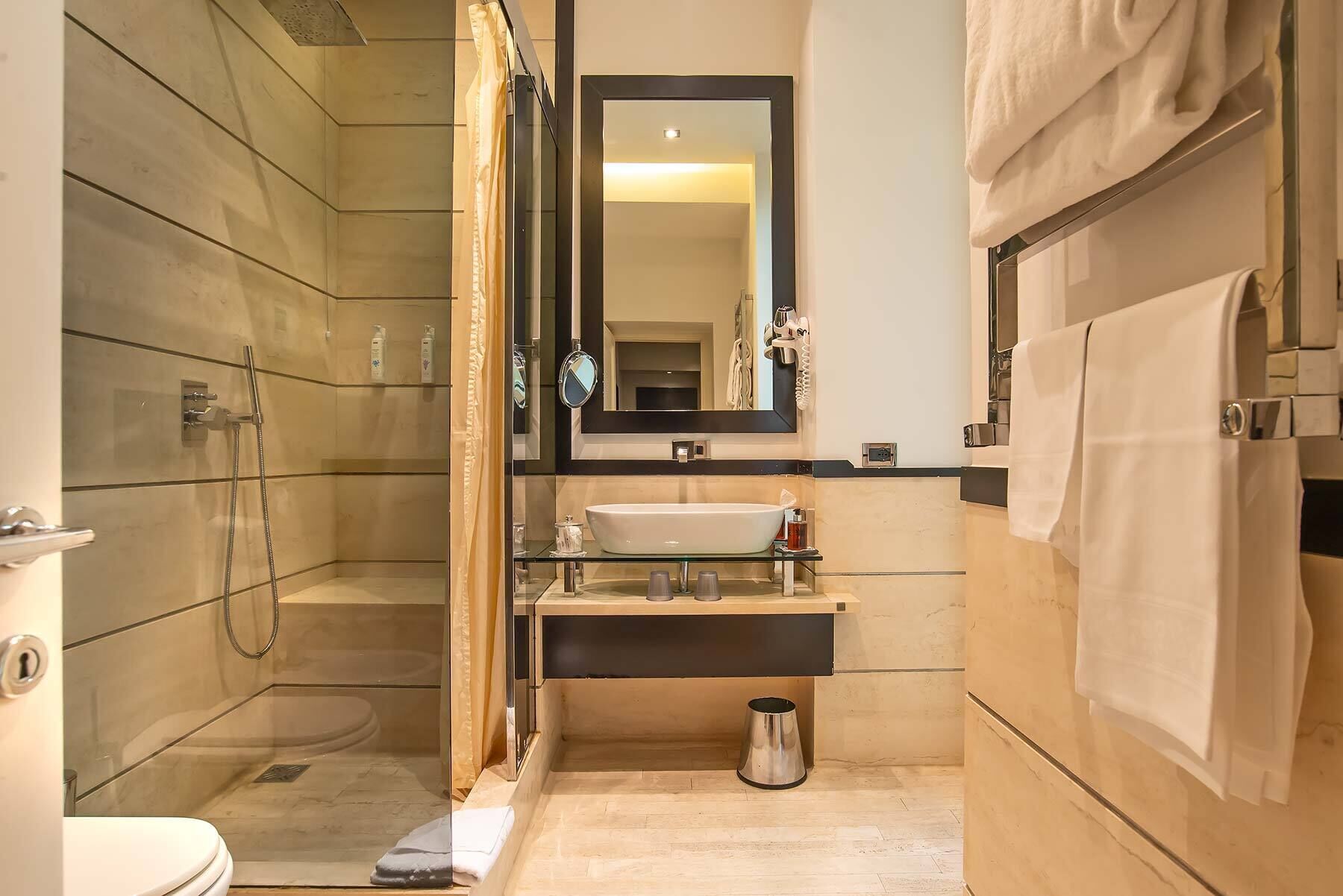Un bagno moderno con doccia vetro, lavandino con specchio sopra e porta asciugamani.