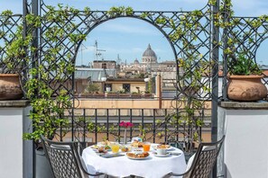 A balcony table with breakfast items, overlooking a cityscape with a prominent dome building. - Hotel Isa (Rome)