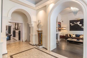 A spacious living area with a marble floor, a large painting, and a modern chandelier.
