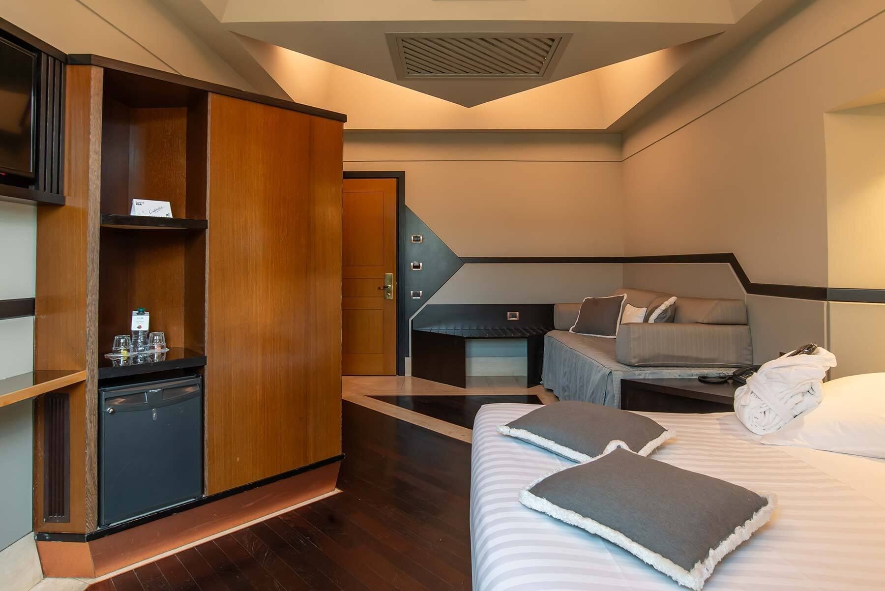 Ein kleines Hotelzimmer mit einem Bett, einer Sitzecke und einem Kleiderschrank.