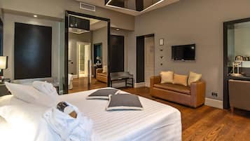 A modern hotel room with a large bed, a sofa, a TV, and a mirror.