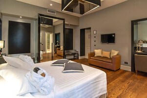 Et moderne hotelværelse med en stor seng, en sofa, et fjernsyn og et spejl.