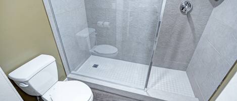 A modern bathroom with a glass-enclosed shower, a toilet, and a sink.
