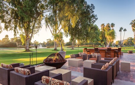 An outdoor seating area with wicker furniture, a fire pit, and a view of a golf course.