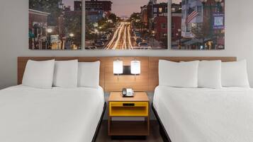 Een hotelkamer met twee bedden, een nachtkastje met een telefoon en een stadsgezicht op de muur.