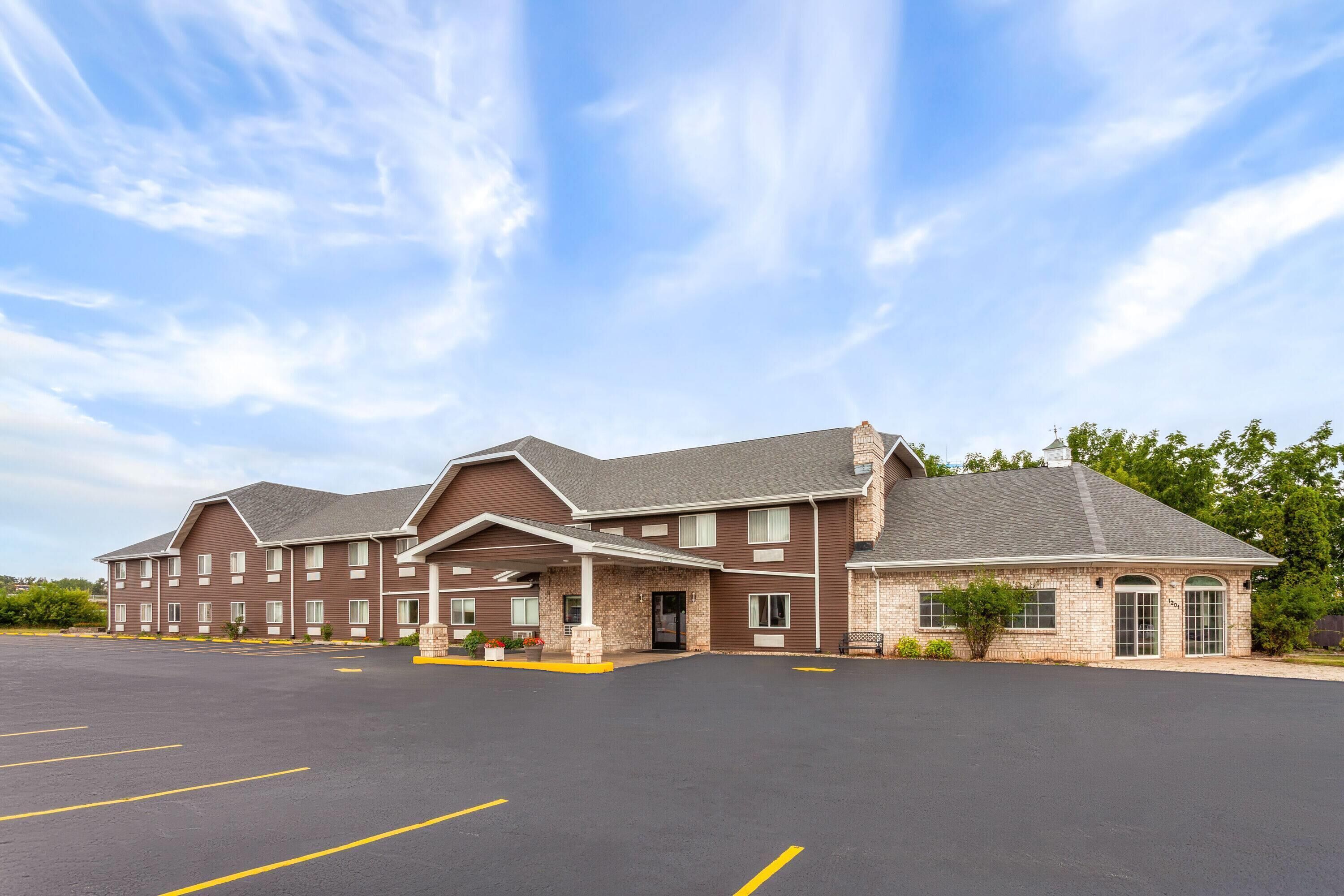 A multi-story hotel with a brick facade and a large parking lot.