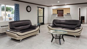 Un salon moderne avec deux canapés en cuir, une table basse en verre et une grande fenêtre agrémentée de rideaux.