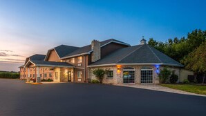 Un grand hôtel à plusieurs étages, doté d’une entrée imposante, d’un patio couvert et d’une pelouse bien entretenue.