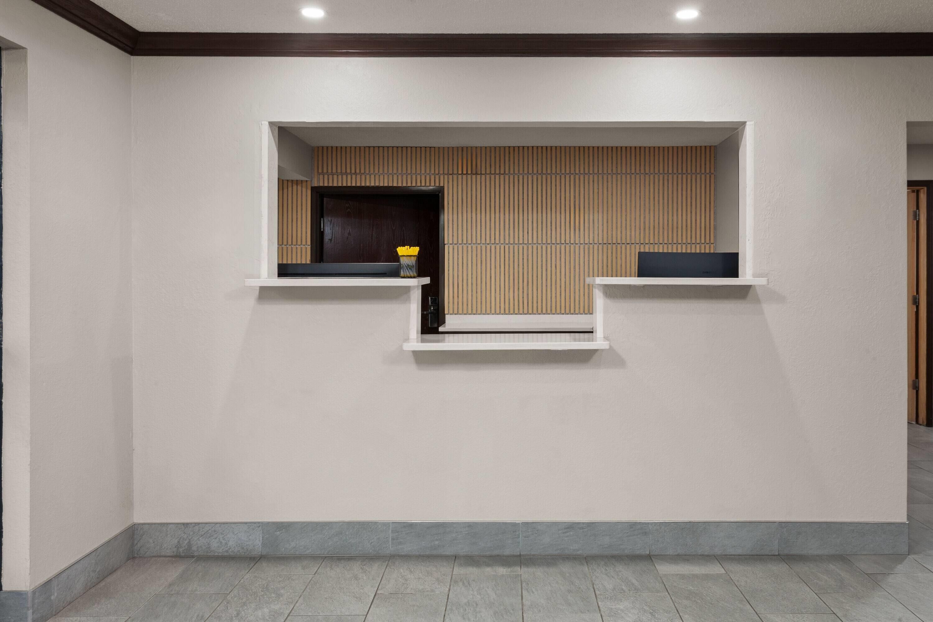 A reception area with a modern design, featuring a reception desk, a wooden panel wall, and a tiled floor.