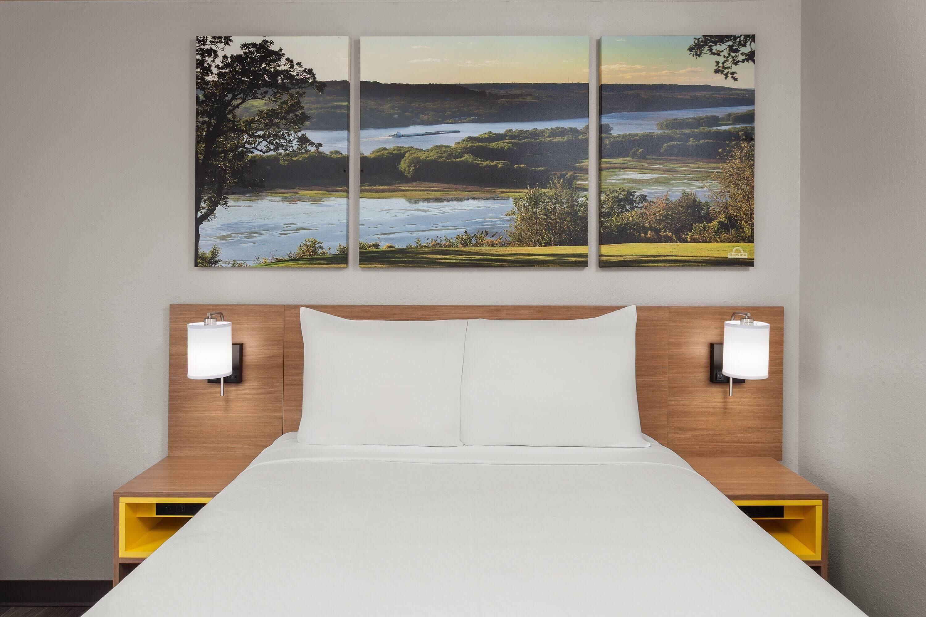A hotel room with a bed, two bedside tables, and a wall-mounted lamp.
