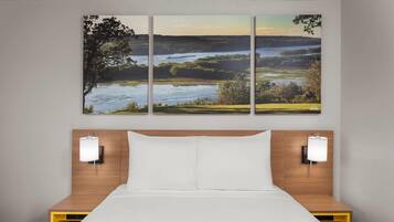 A hotel room with a bed, two bedside tables, and a wall-mounted lamp.