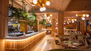 Un restaurante con una barra larga, plantas colgantes y varias mesas y sillas.