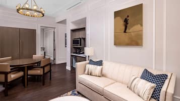 Una sala de estar moderna con un sofá color beige, una mesa de comedor con sillas, una araña y un cuadro en la pared.