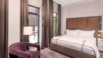 A hotel room with a large bed, a chair, a nightstand, and a window with curtains.