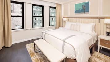 A hotel room with a large bed, a bench, a nightstand, and a painting on the wall.