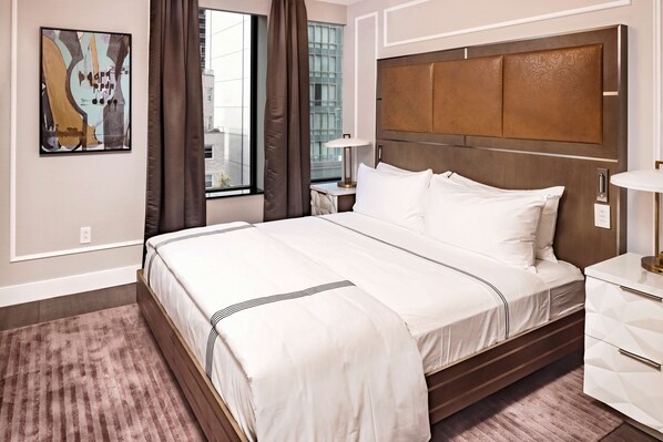 A hotel room with a large bed, a nightstand, a lamp, and a window with curtains.