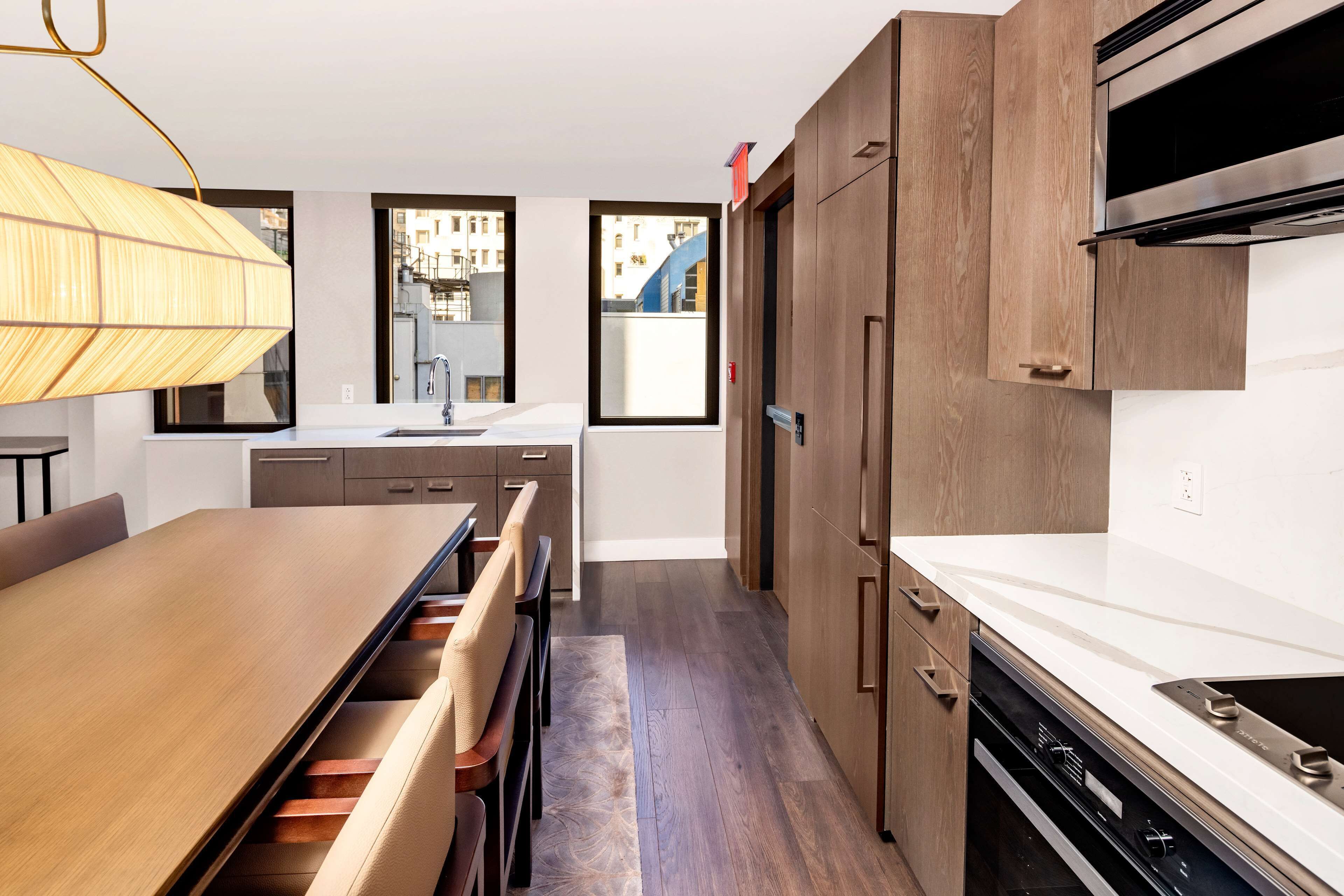 A modern kitchen with wooden cabinets, a built-in oven, and a large dining table with chairs.