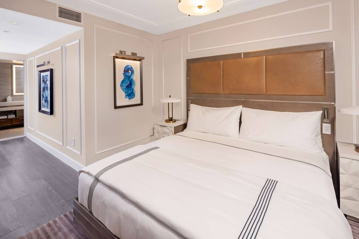 Een hotelkamer met een groot bed, een nachtkastje en een wandlamp.