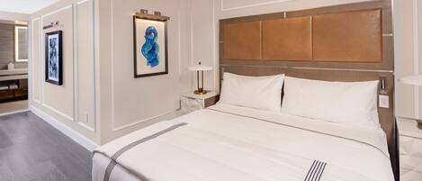 A hotel room with a large bed, a nightstand, a bedside table, and a wall-mounted lamp.