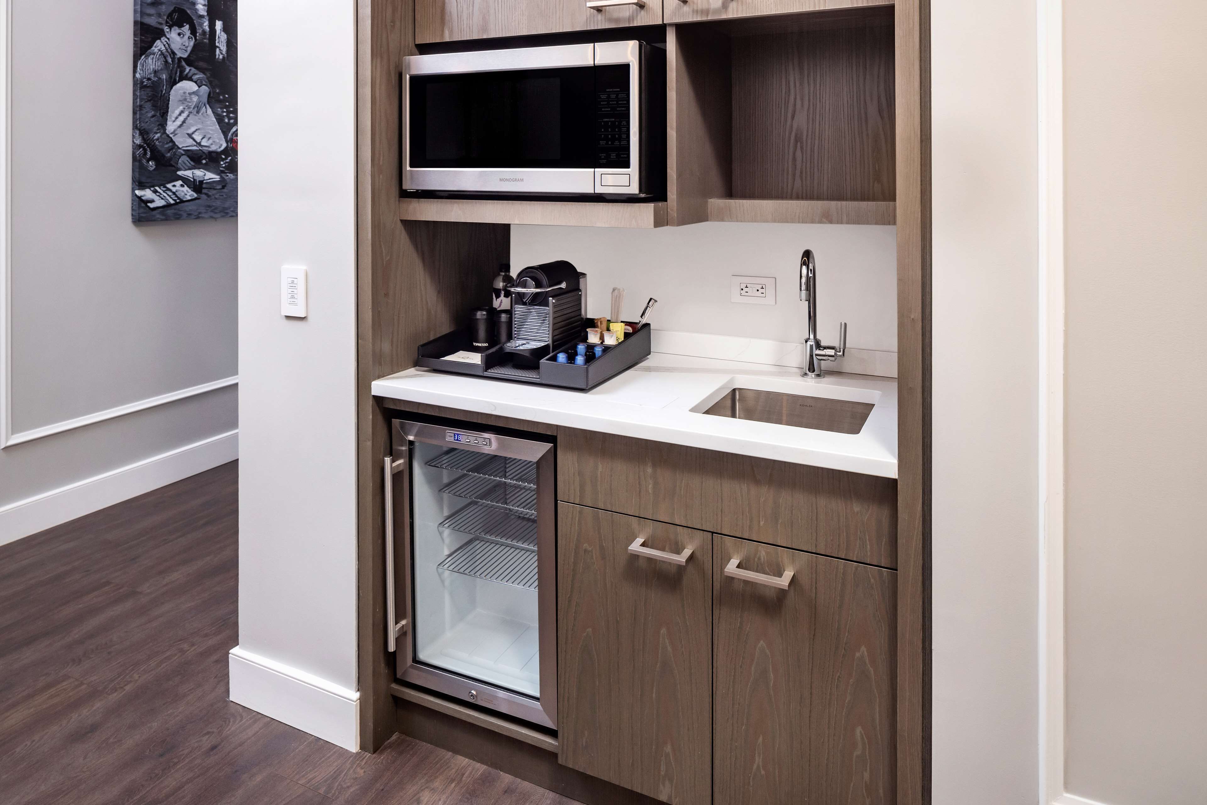 A compact kitchen with a built-in microwave, a sink, and a mini-fridge.