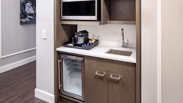 A compact kitchen with a built-in microwave, a sink, and a mini-fridge.