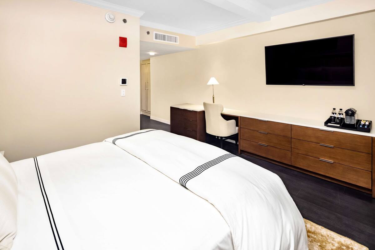 Een hotelkamer met een bed, bureau, stoel, televisie en een minibars.