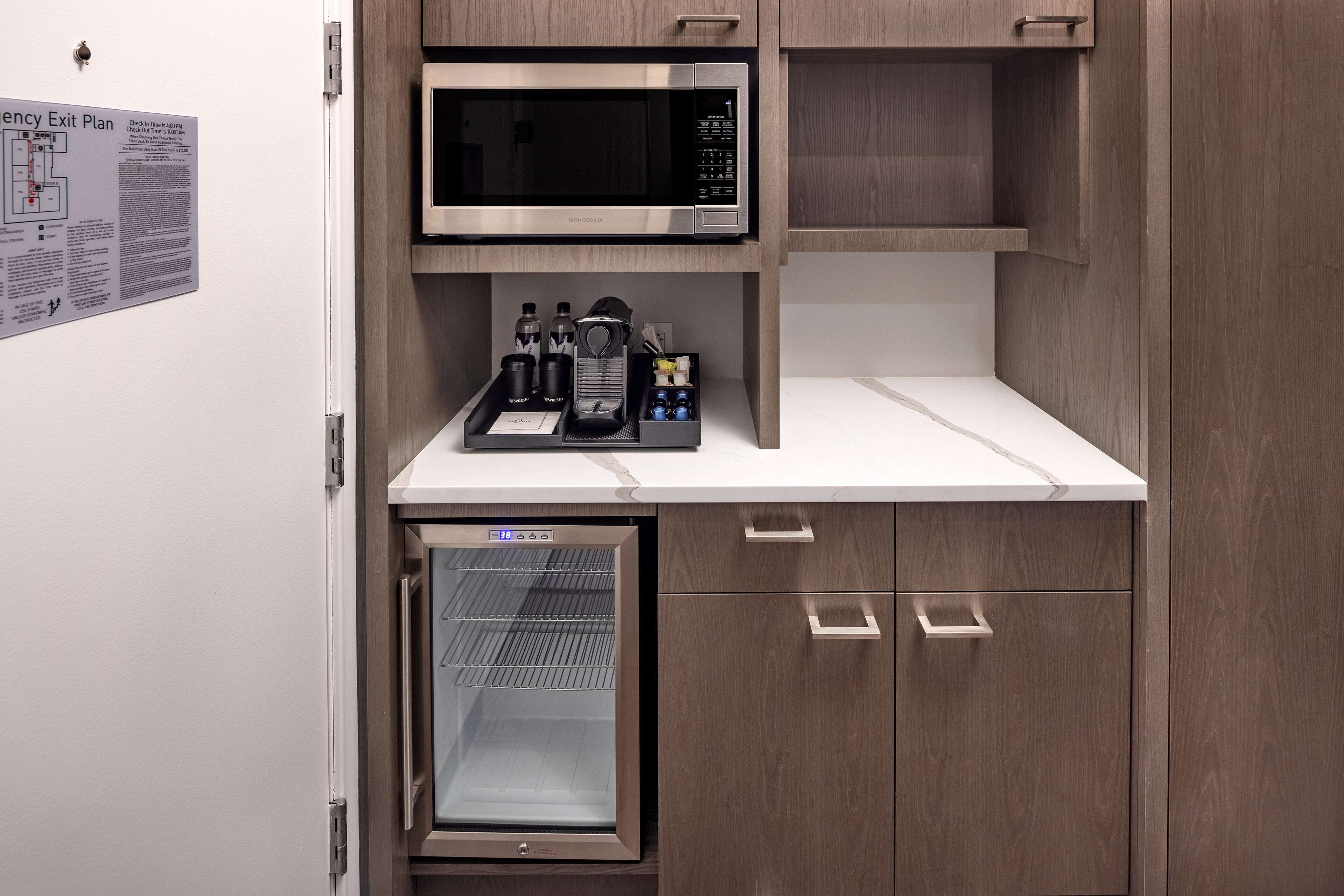 Una kitchenette compacta equipada con microondas, un mini refrigerador y cafetera.