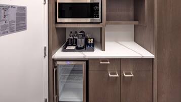 Una kitchenette compacta equipada con microondas, un mini refrigerador y cafetera.