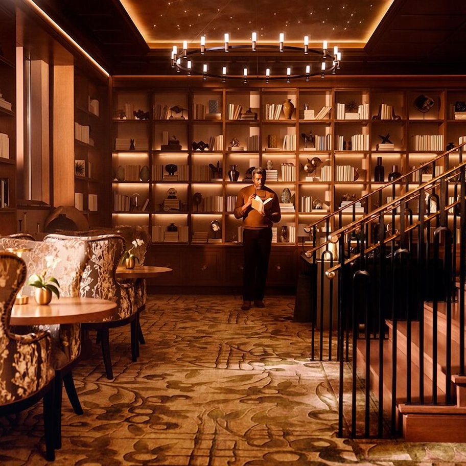 A library with bookshelves, a staircase, and seating areas.