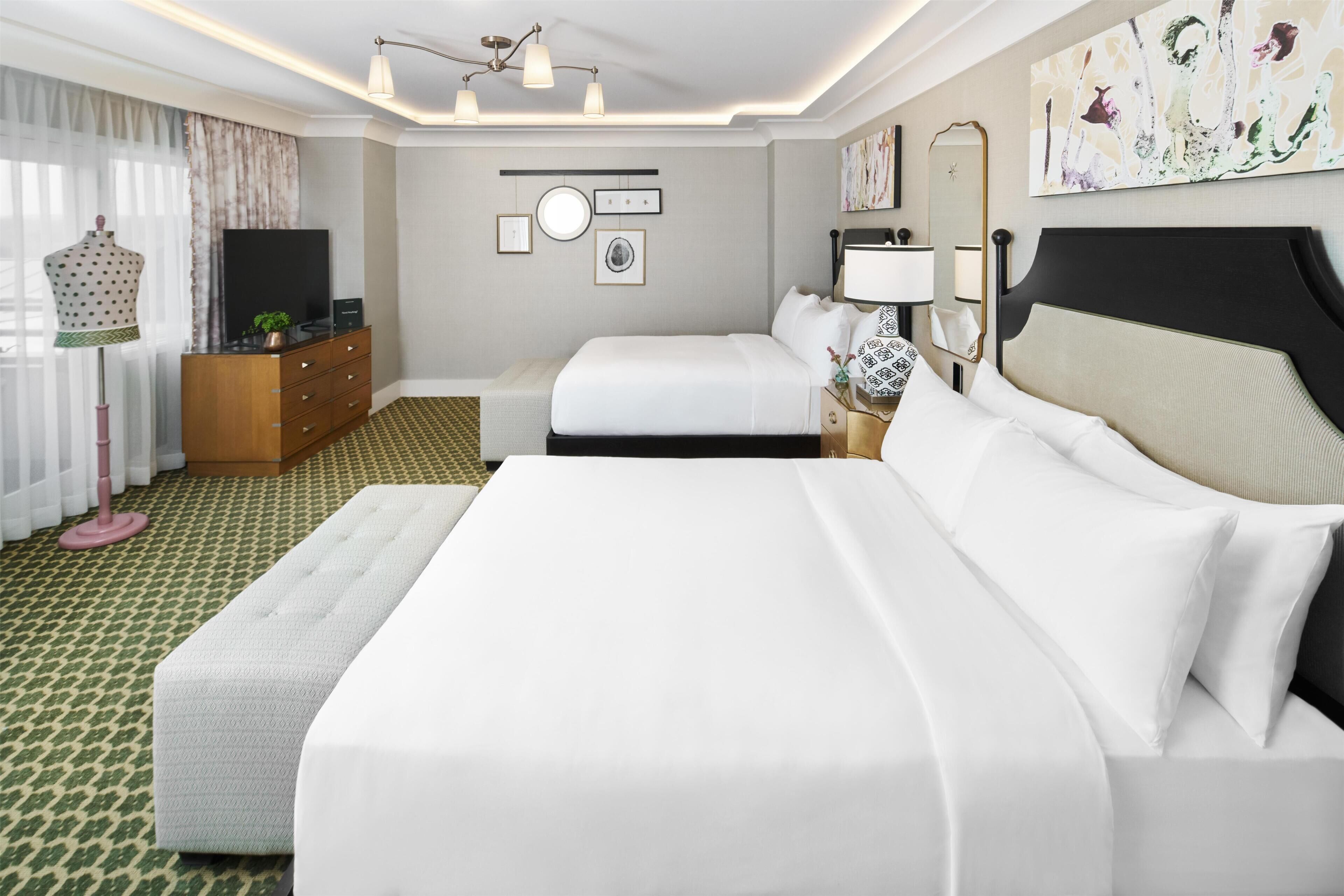 Et hotelværelse med en stor seng, et kommode, et fjernsyn og et spejl.