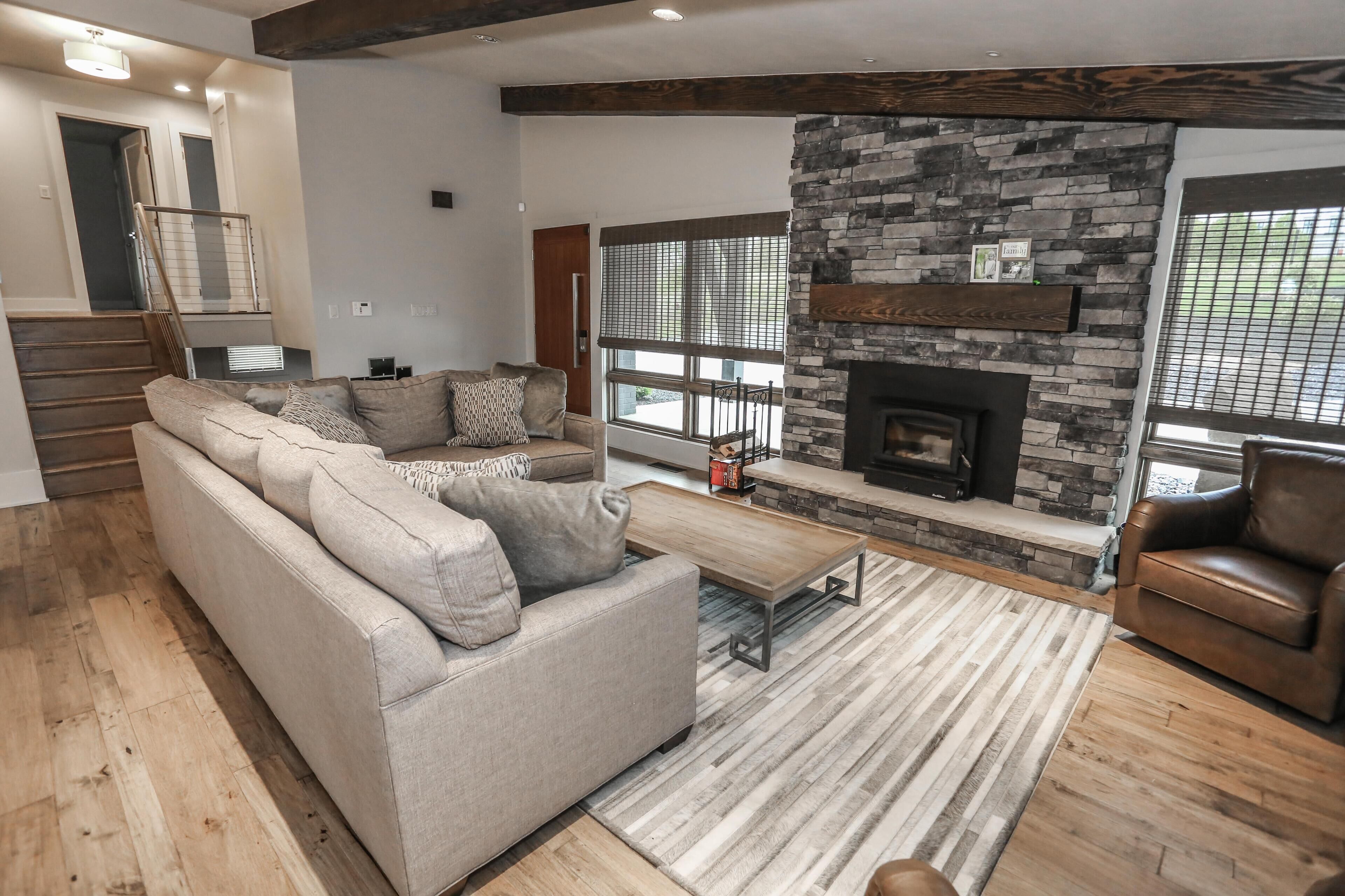 A living room with a sofa, a coffee table, a fireplace, and a stone accent wall.