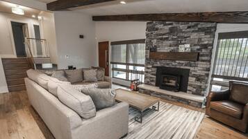 A living room with a sofa, a coffee table, a fireplace, and a stone accent wall.