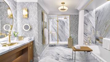 Un baño lujoso con piso de mármol, detalles dorados y diseño moderno.