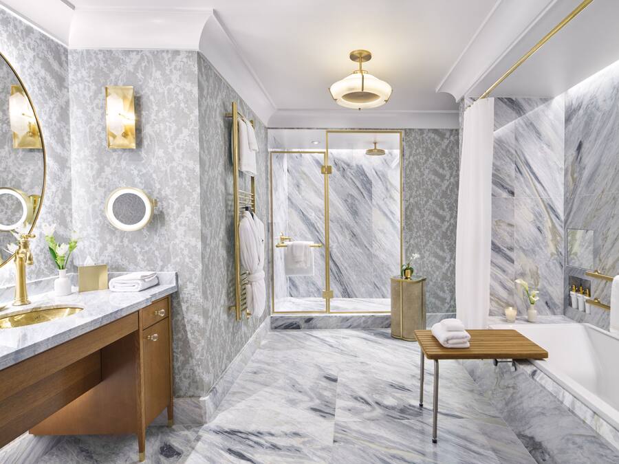 Un bany de luxe amb terra de marbre, detalls daurats i un disseny modern.