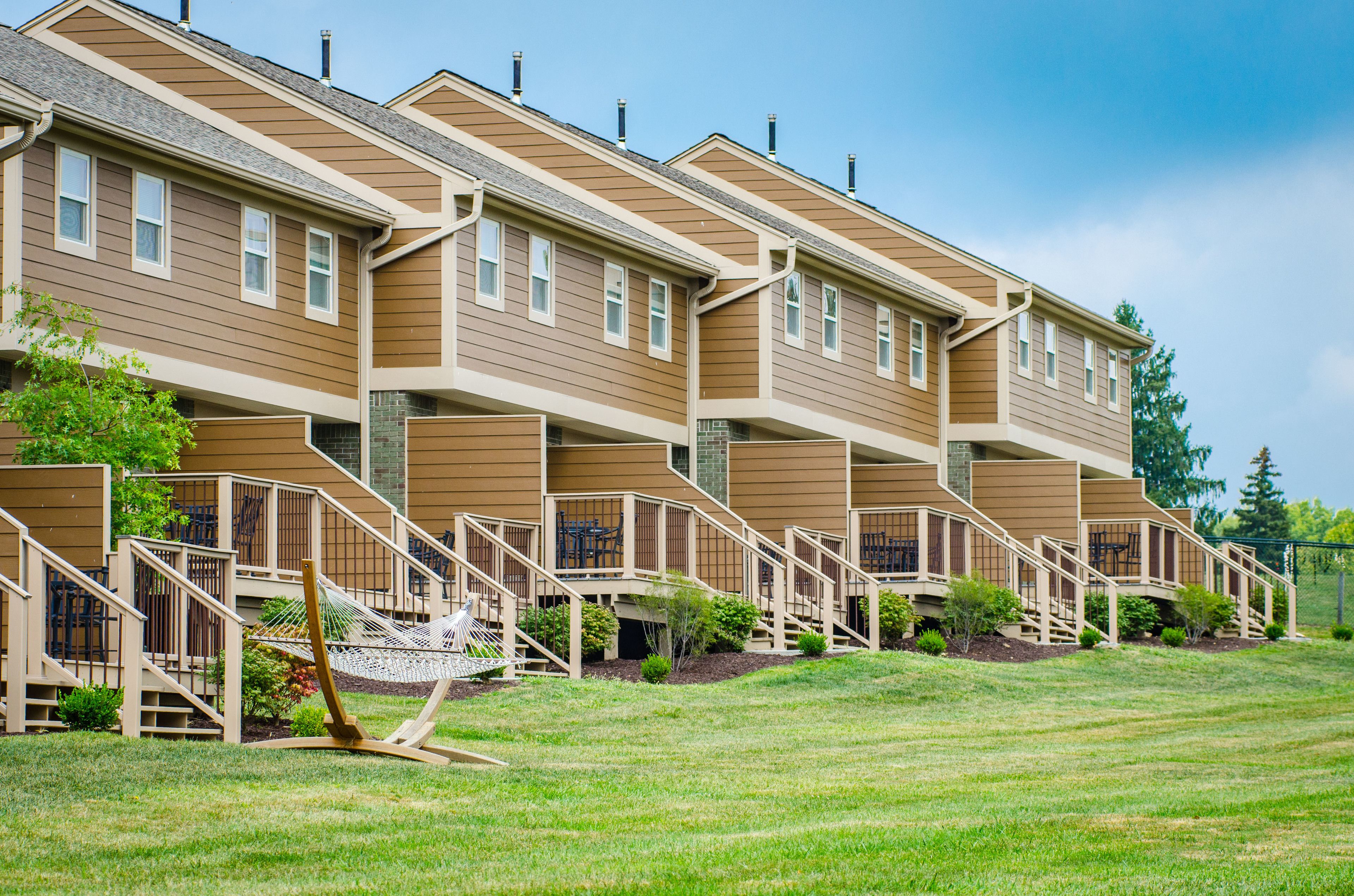 A multi-story residential building with a uniform exterior, multiple balconies, and a well-maintained lawn.