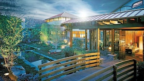 A modern house with a wooden deck, a garden with a pond, and a mountain backdrop. - Nemacolin (Farmington)