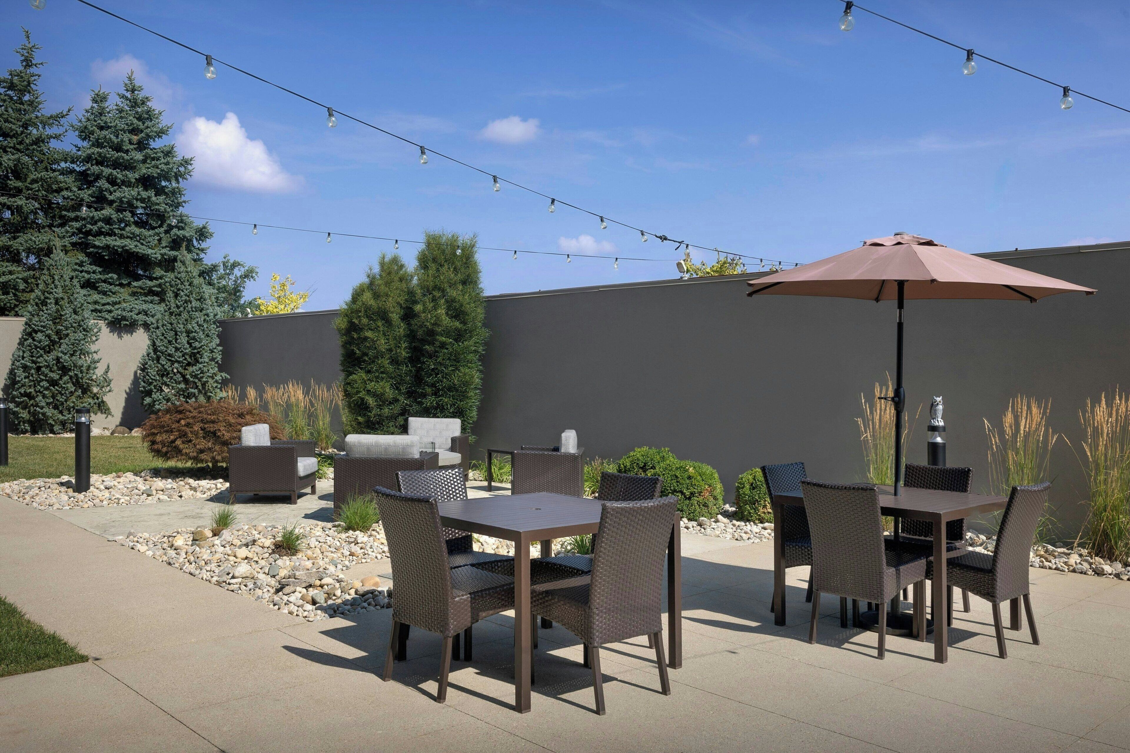An outdoor patio with wicker furniture, a table, and an umbrella.