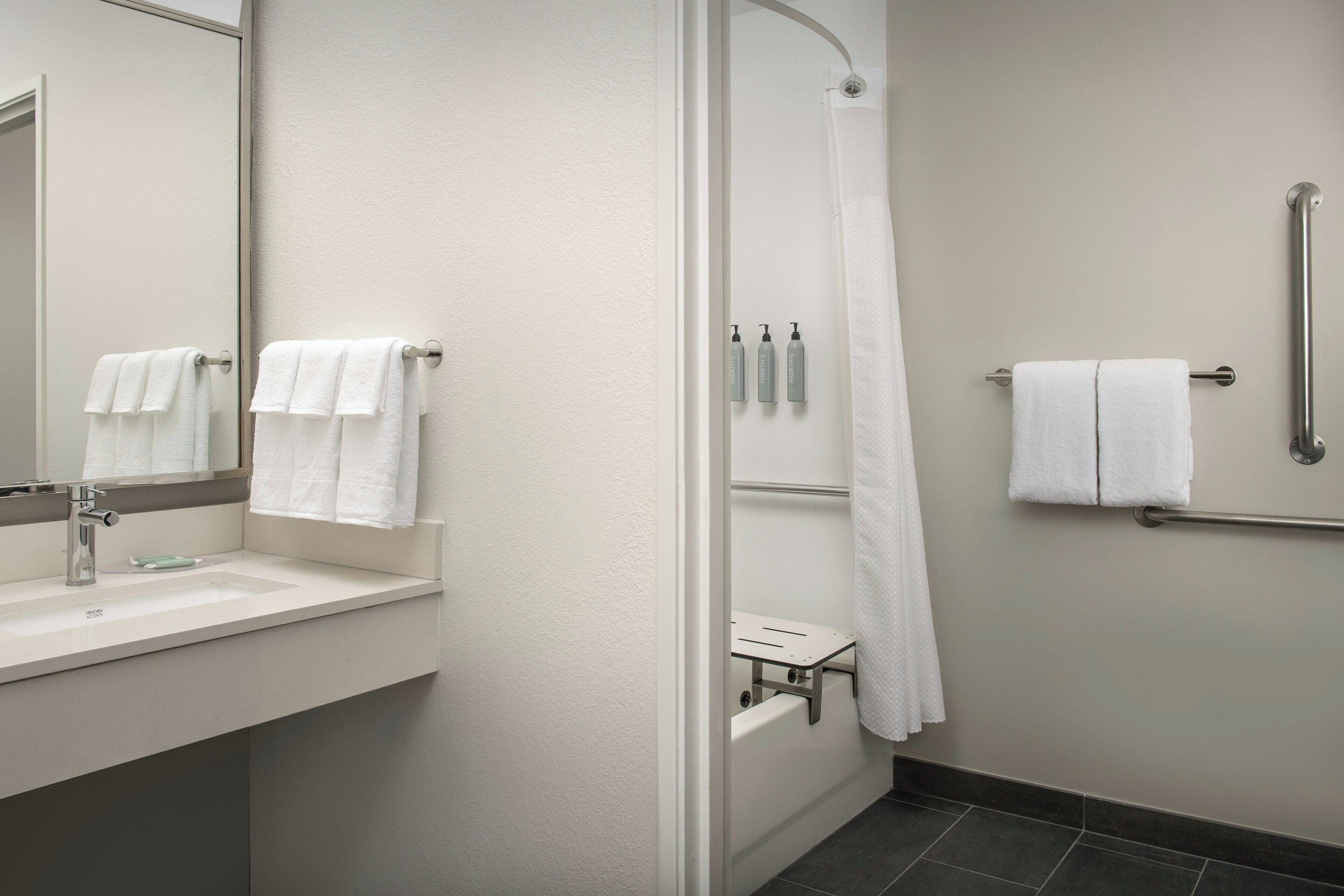 Un baño moderno con lavamanos, espejo y zona de ducha.