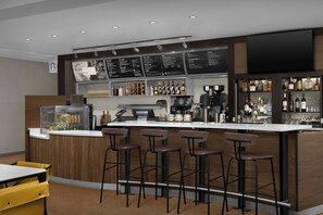 Een bar met krukjes, een koffieapparaat en een menubord.