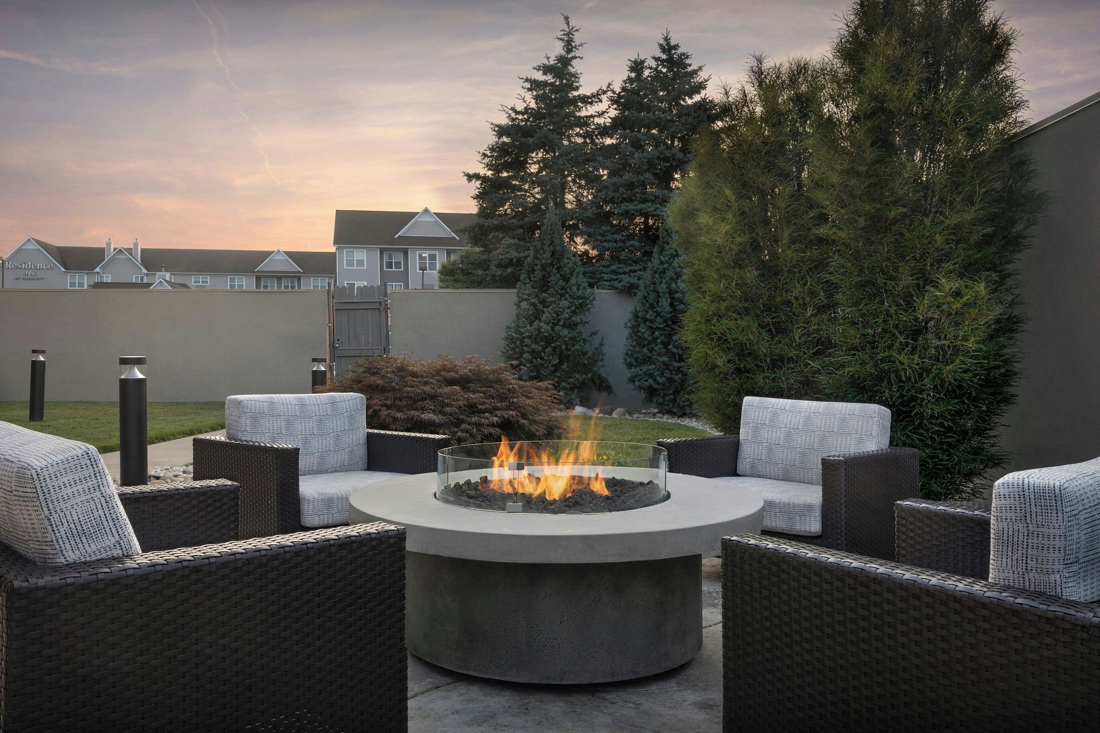 Un espacio de estar al aire libre con muebles de mimbre y una chimenea central.