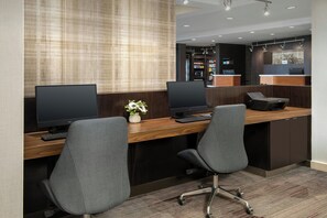 Un espace d’accueil avec deux bureaux, des ordinateurs et une petite plante.
