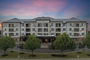 Een meerlaags hotel met een plat dak, een overdekte ingang en een bord waarop 'COURTYARD BY MARRIOTT' staat.