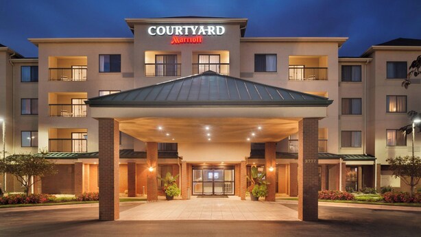 Un hôtel Courtyard Marriott doté d’une entrée abritée, de nombreux balcons et d’une façade en briques.