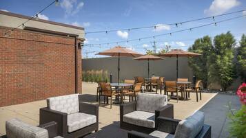 An outdoor patio with wicker furniture, umbrellas, and string lights.