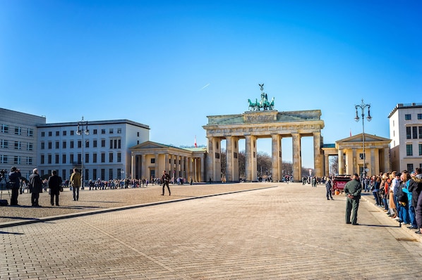 Une vaste place publique, avec un monument historique imposant au centre, entourée de bâtiments.
