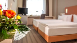 Une chambre d’hôtel avec deux lits, un bureau avec un ordinateur et une télévision.
