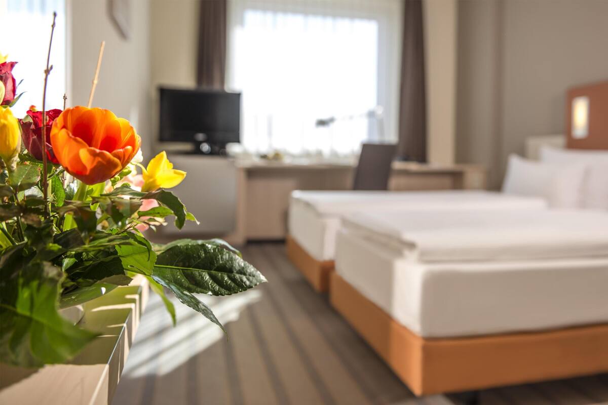A hotel room with a bed, a desk, a television, and a window with curtains.